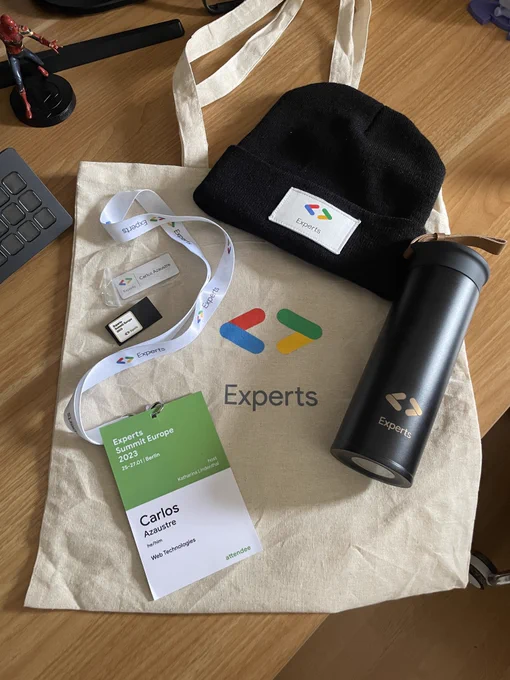 Bolsa de swag / merchandising del programa Google Developer Experts. Aparece la bolsa, la acreditación del evento al que no pude acudir, un termo, un gorro de lana negro, un pin del evento y una chapa imantada con mi nombre y el logo de GDE.