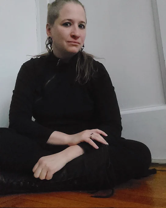 Me sitting cross legged on the floor. I am looking directly at the camera with a slight smile. 