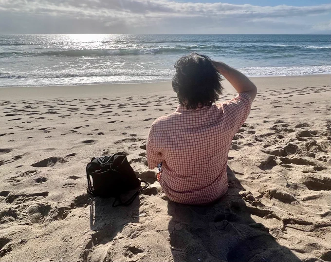 Brian sitting on a beach, looking out over the horizon
