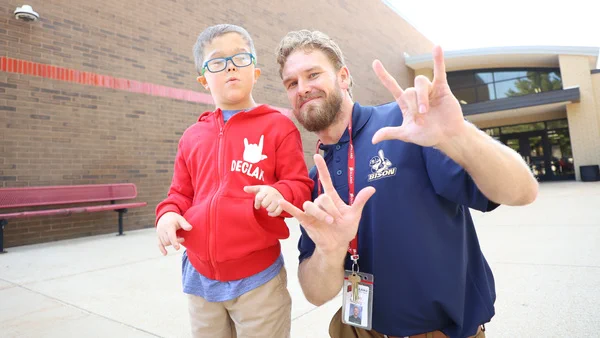 Image of a man with a young boy, both using the sign language word love