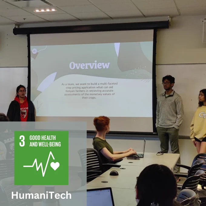 Three students stand at the front of a classroom and present a presentation on a screen. 