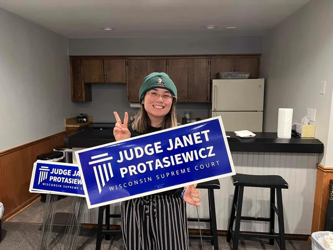 A woman poses with a Judge Janet Protasiewicz sign. 