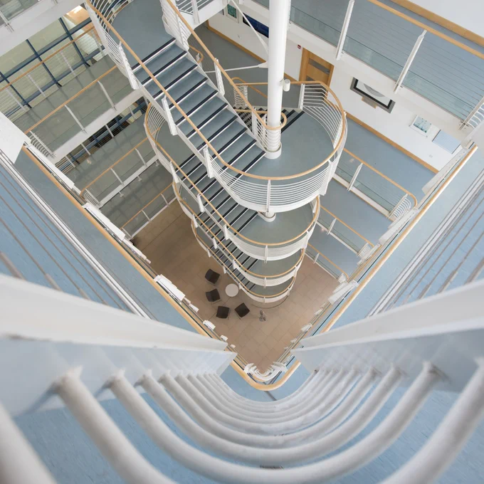 A stairwell viewed from above with multiple flights of stairs rising through an atrium