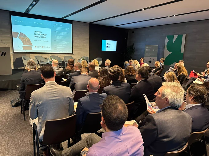 Image of seated crowd in conference room onlooking projector screen