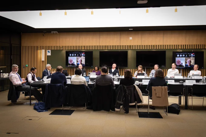 Wide shot of the final meeting, with meeting attendees in a discussion. 