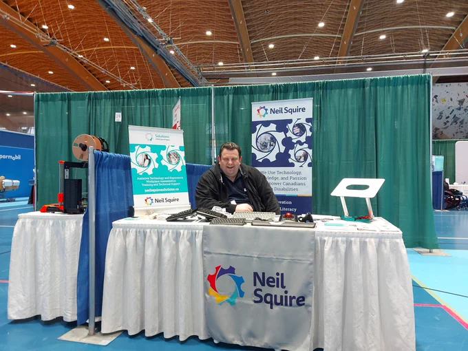 Gordon at the Neil Squire booth, with posters and brochures for our Solutions program, as well as assistive technology