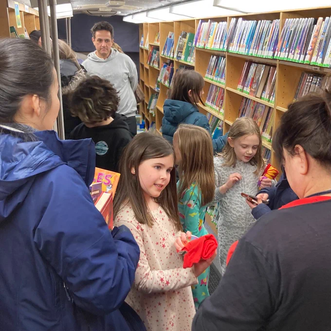 IMAGE: children and adults gathered on the Bookmobile picking out books.