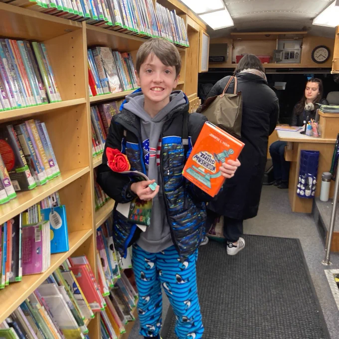 IMAGE: A boy holding up a book he found on the Bookmobile.