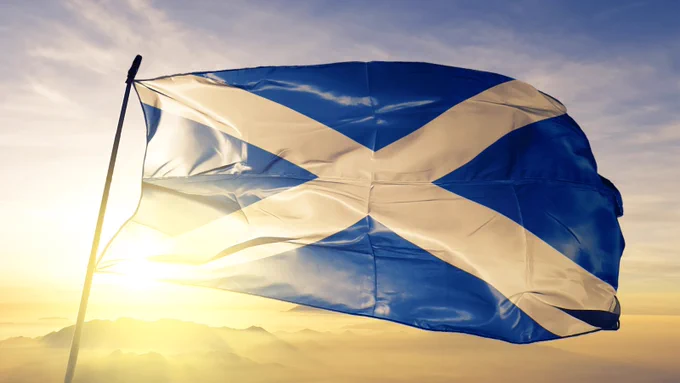 Photo of the Scottish flag flying on a pole on a sunlit sky