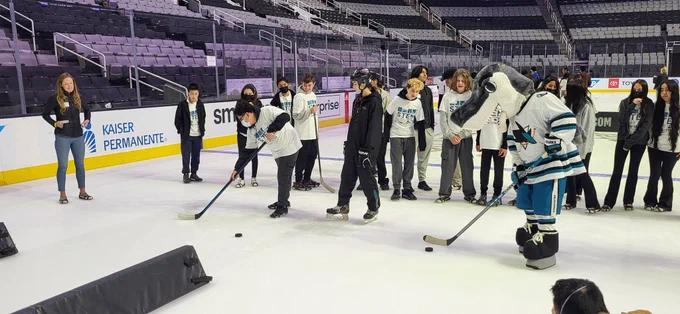 Sharkie and a group of students doing hockey drills