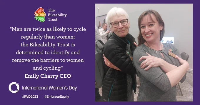 Bikeability Trust CEO Emily Cherry and Chair of Trustees Alison Hill are posing for International Women's Day. They are embracing themselves in a self-hug, with arms across their upper body. A quote reads: Men are twice as likely to cycle regularly than women; the Bikeability Trust is determined to identify and remove the barriers to women and cycling.