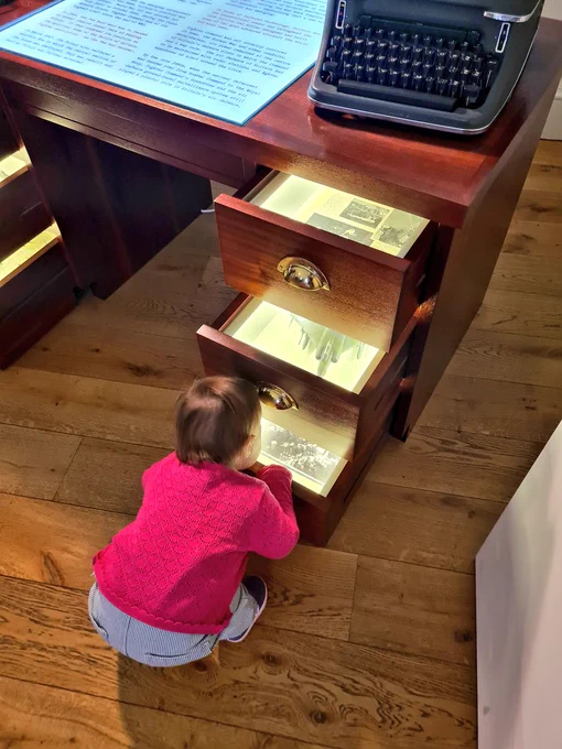 Toddler explores museum displays of planes inside desk drawers