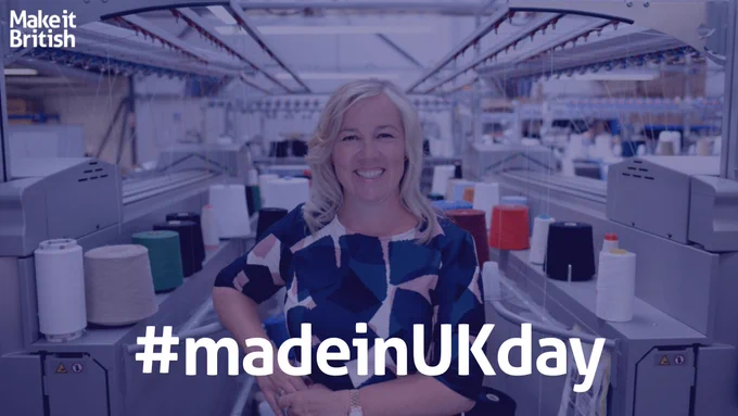 Kate Hills stood in front of a garment factory with the word #madeinukday in the middle in white.