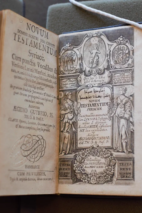The cover page of the Syriac New Testament. Two figures stand alongside the title of the book. A baby with a cross is at the top of the page.