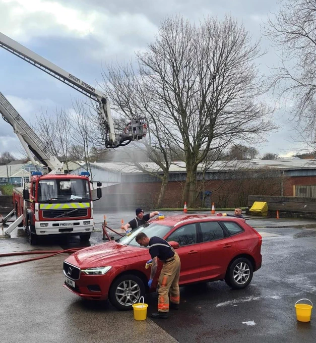 3 Fire Fighters cleaning a red car