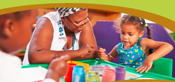 Image shows a woman sitting with a small child, working together on some artwork.