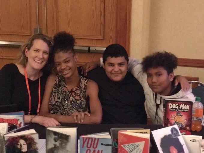 Julie, Jaida, Jose, and Cesar presenting at NCSLMA. Sitting at table with arms around each other.