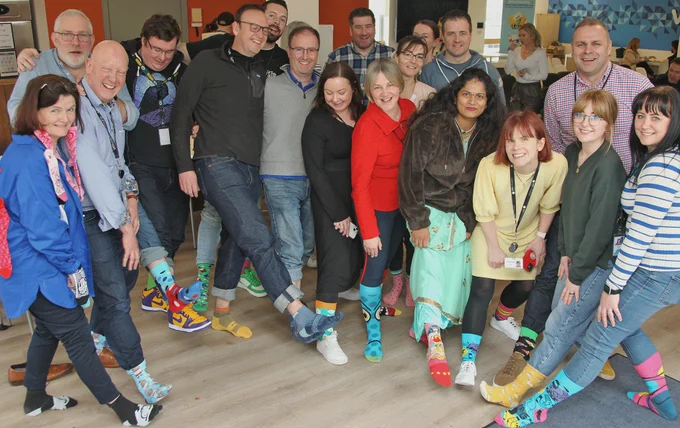 Group of people posing wearing colorful socks 