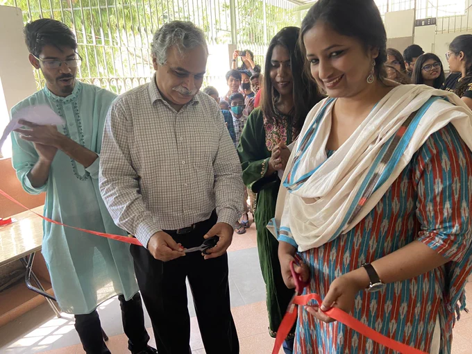 Image 1: Dipendra and Prasann ji cut a red ribbon to inaugurate the UAL project. Library members and staff are in the background.