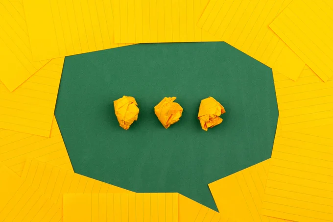 Graphic made with yellow note paper and green card featuring speech bubble with ellipsis in the centre