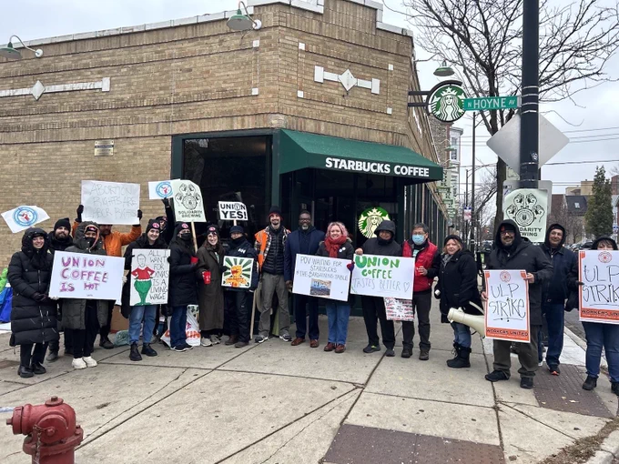 Brandon stands with Starbucks workers outside a Starbucks in bucktown, circa 2022. Workers are holding signs that say “strike” and “union yes”.