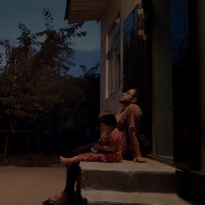 Man and his daughter sitting on a stoop 