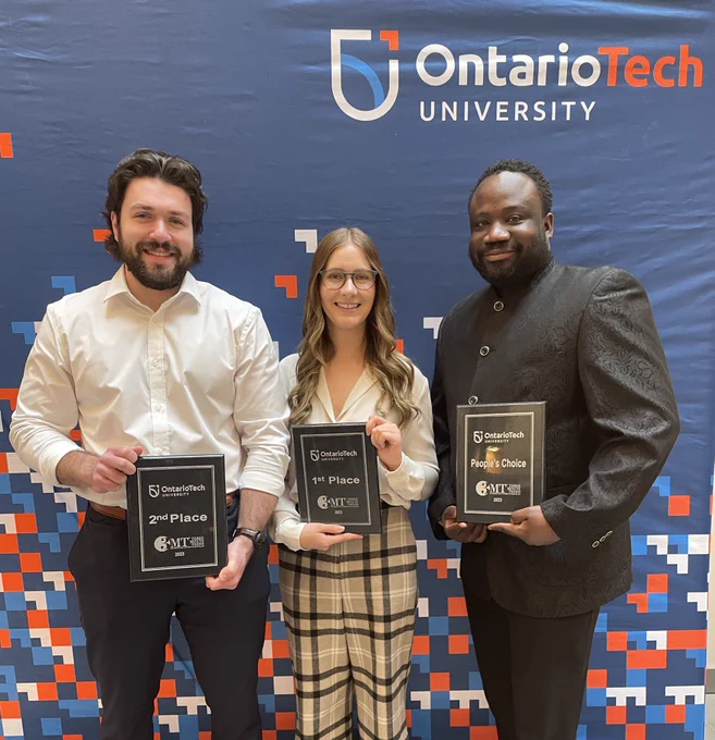 Colin, Sarah and Bismark hold their plaques and stand in front of an Ontario Tech backdrop.