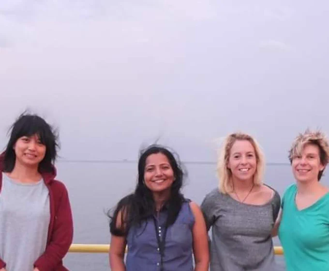 Photo of 4 people on top of a ship in windy conditions 