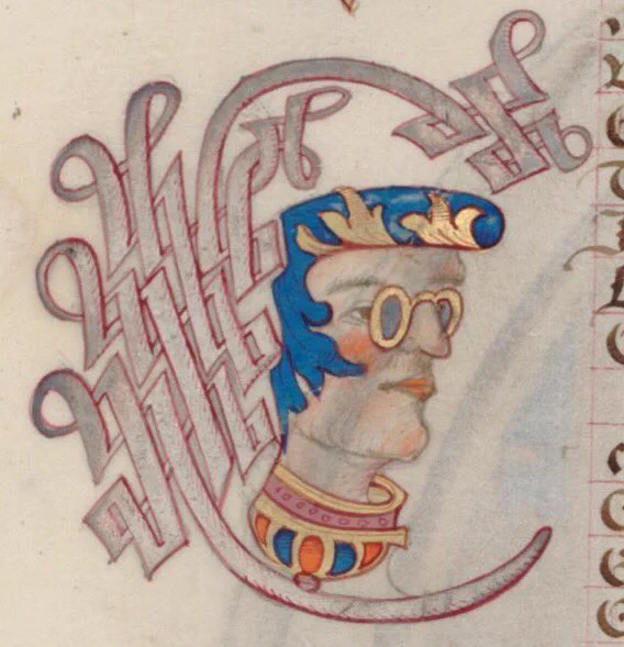 A 16th century ink drawing of a man’s head. He is wearing dark glasses and his hair is made out of a blue and gold ornament that resembles a pompadour.