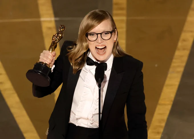 A photo of writer-director Sarah Polley, dressed in a tuxedo and holding her Oscar on stage.