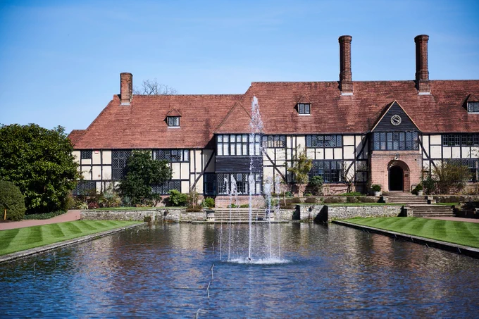 Arts and Crafts style building in front of an artificial pond with a fountain