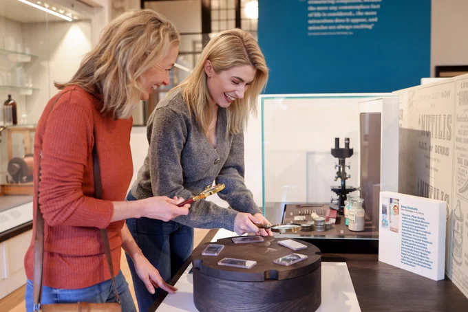 Two people holding magnifying glasses and looking at a display in the old lab