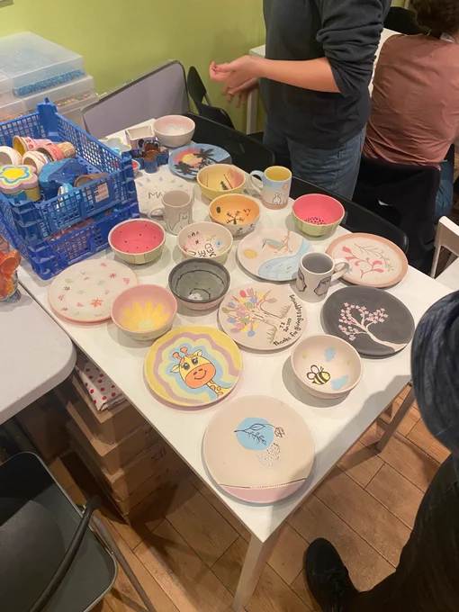 Picture shows a table displaying all pottery works. There are colourful plates, bowls and mugs.