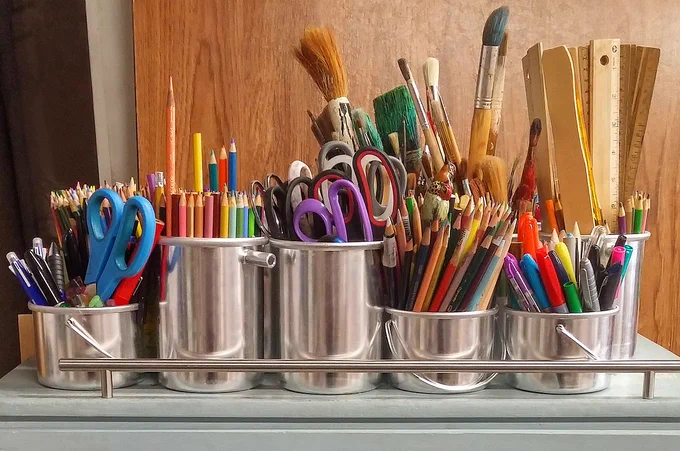 Lots of creative tools in tin cans- rulers, colourful pencil, brushes and scissors. 