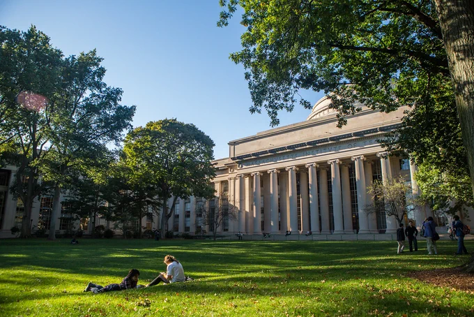 Two people sitting on the grass in Killian Court.