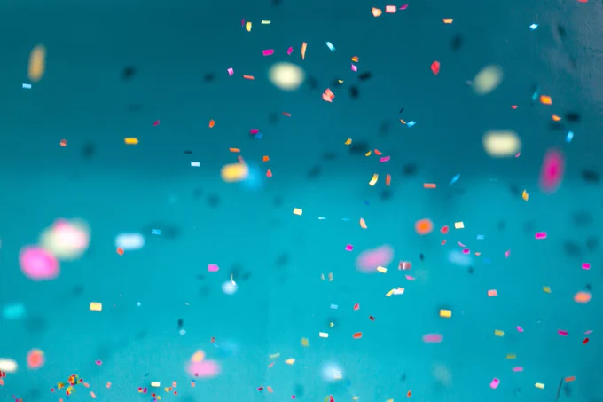 Confetti in the air with a blue background.