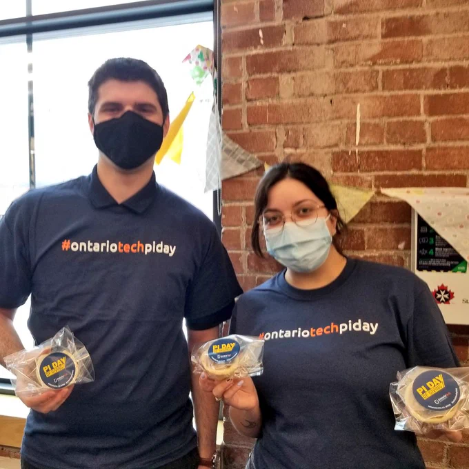 Two people hold mini pies. Their shirts read #OntarioTechPiDay