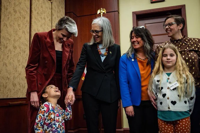 Democratic Whip Katherine Clark stands alongside Equal Pay advocates at a press conference. The group includes professional soccer player KJ Spisak, Department of Labor Director Chun-Hoon, and two young girls. 