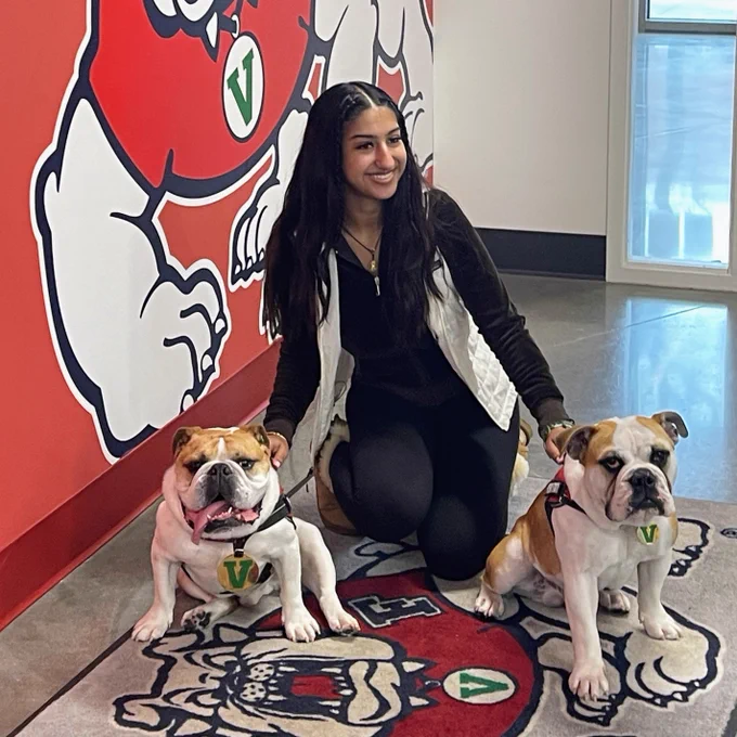 Student posing with two live mascot dogs.