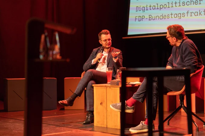 Maximilian Funke-Kaiser und Sascha Friesike diskutieren an einem kleinen Tisch auf der Bühne. 