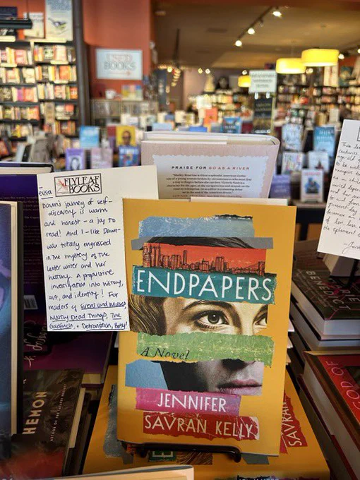 Endpapers standing up on a table in Flyleaf Books bookstore. Behind it is a note describing the book and recommending it to readers of SIRENS & MUSES, MOSTLY DEAD THINGS, THE GOLDFINCH, and DETRANSITION, BABY.