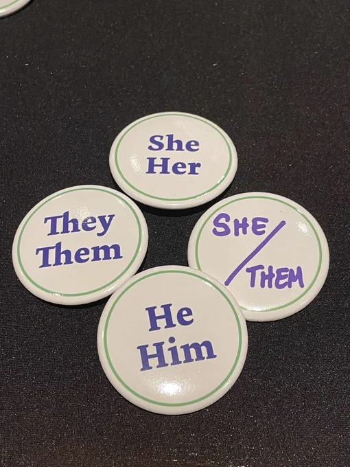 Images of buttons with preferred pronouns - She/Her, She/Them, They/Them, He/Him