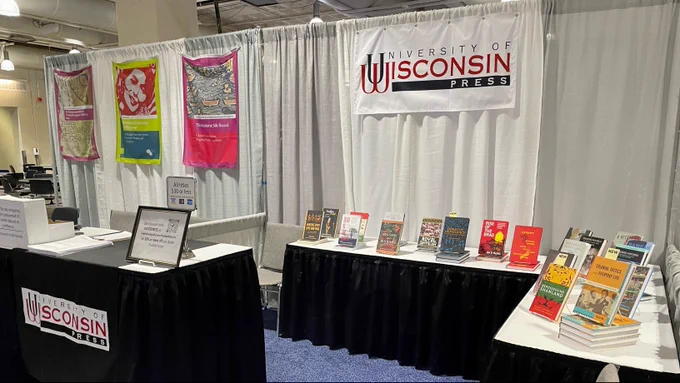 An L-shaped table in the UW Press booth at AAS 2023 in Boston, with many of our recently published books, and on the left, our information table