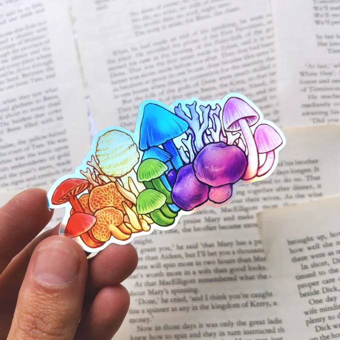 me holding a sticker that is a row of mushrooms in rainbow order