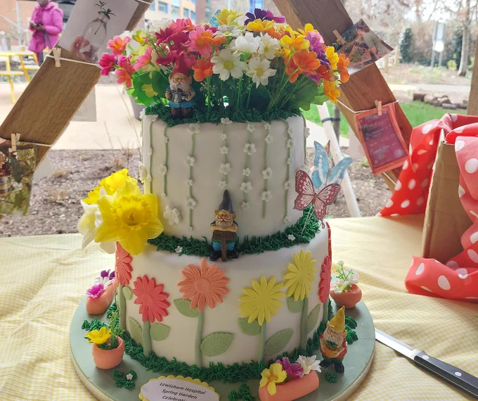 A two-tier cake decorated with flowers and gnomes