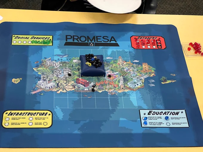 Promesa board game: a neoprene mat with an illustrated map of the archipelago of Puerto Rico, with game pieces (a rubber platform with plastic gems, and other gems on the board itself). 