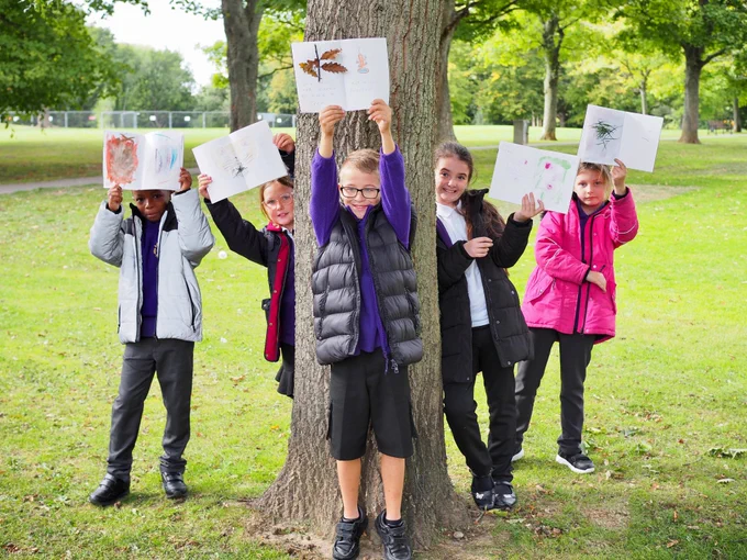  Photograph: A group of school children holding up art work they have created.