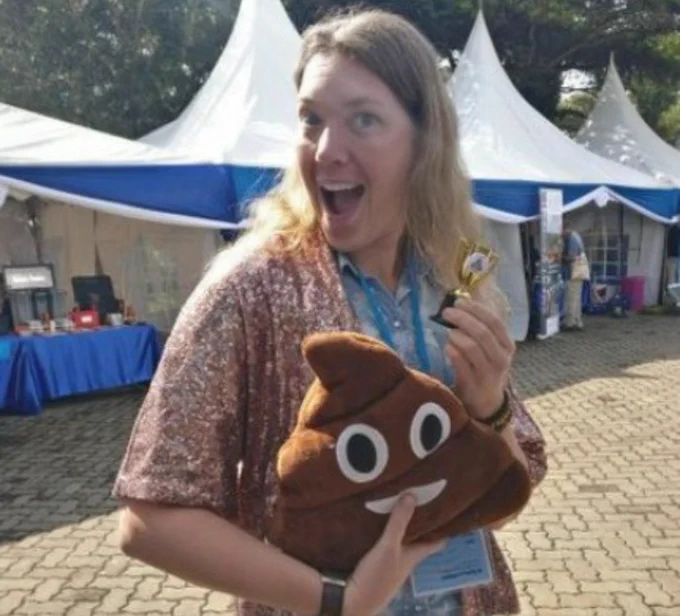 Becky in gameshow host mode with a sparkly jacket, a plush poop emoji, and a tiny trophy!