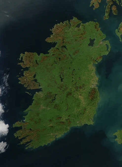 A vertically-oriented image of Ireland, as seen from space. The photo is almost completely free of clouds, except for a few wisps in the bottom-left, so the lush greens of the island stand out against the dark-blue water surrounding it. NASA image courtesy Jeff Schmaltz, MODIS Rapid Response Team, Goddard Space Flight Center.
