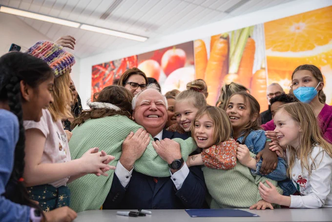 Children hug a man and smile